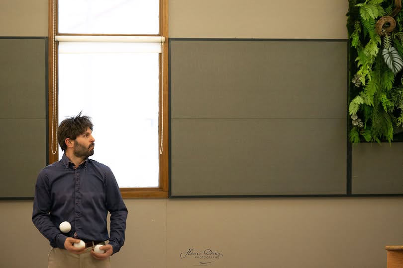 Photo illustrant le spectacle en cours de création "Les bras croisés". On y voit un homme, seul près d'une fenêtre, des balles de jonglage à la main.