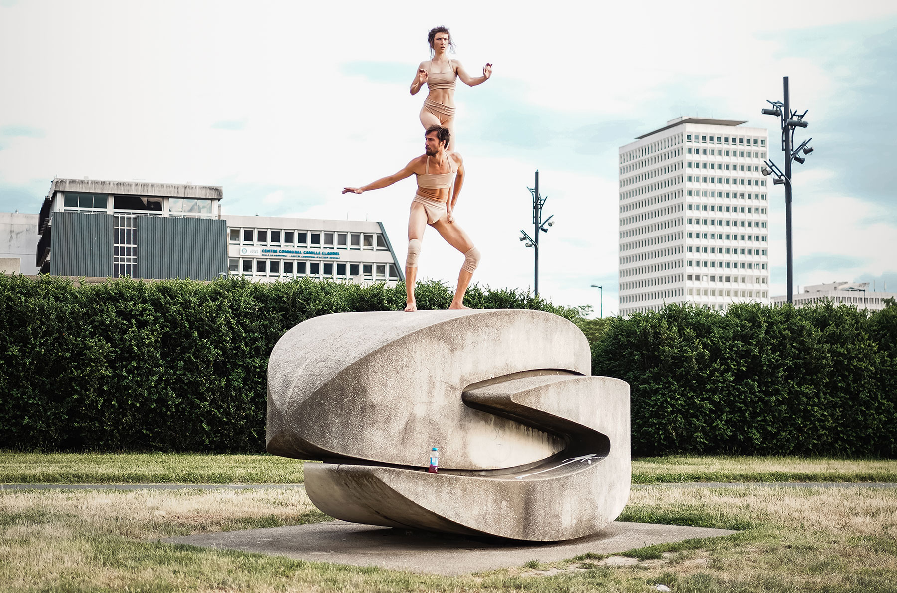 Ce visuel illustre le spectacle "Obaké". 2 acrobates sont perchés l'un sur l'autre, sur une sculpture monumentale posée dans l'espace public.