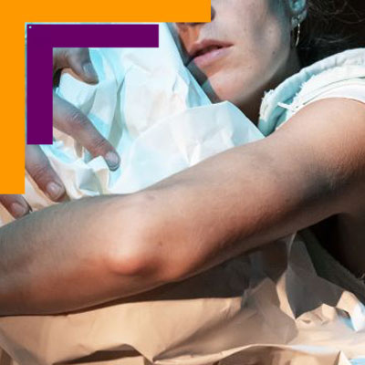 Visuel du spectacle "Papiel". On voit une femme en gros plan, qui semble dormir, avec du papier froissé entre les bras, comme une peluche ou un oreiller.