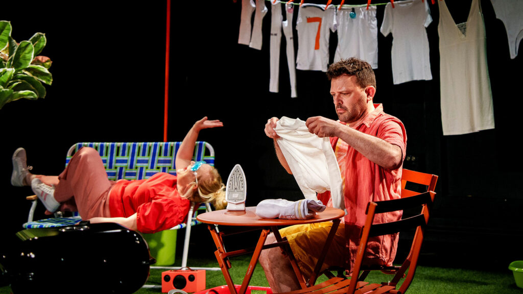 Le visuel illustre le spectacle "Mercredi c'est sport". On y voit 2 personnages dans un décor vintage. Un qui repasse son maillot de foot - les autres sèchent sur un fil - et sa mère qui se repose sur un canapé.