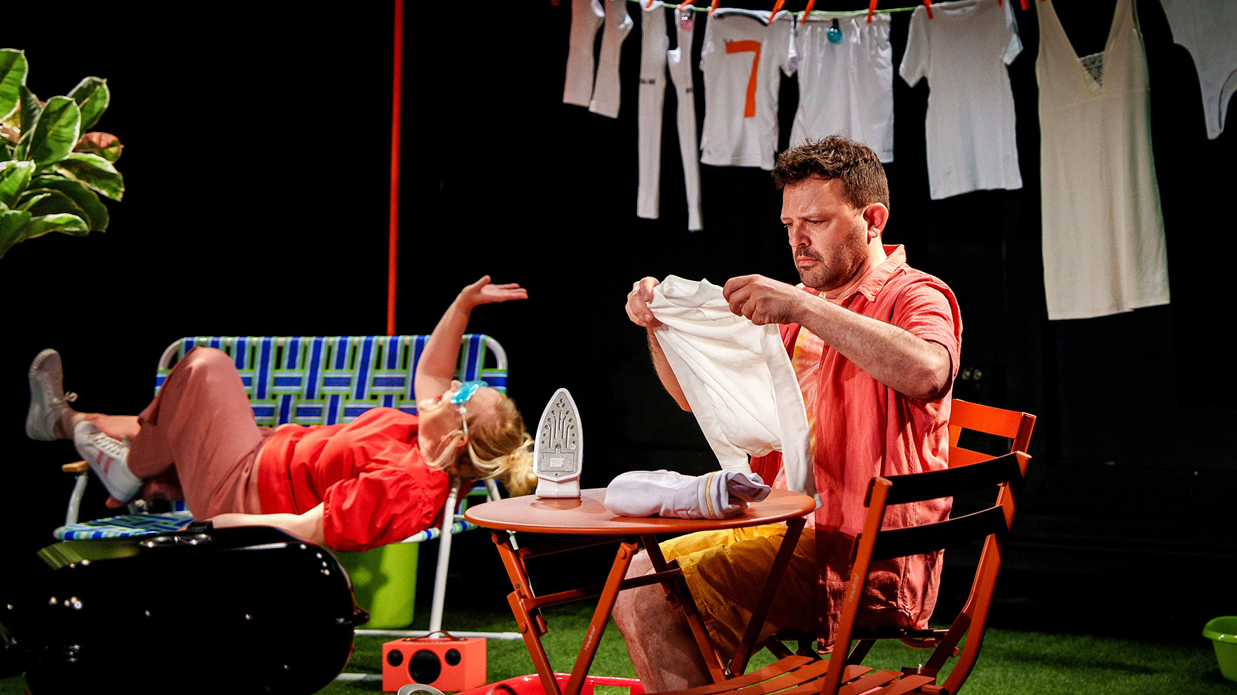 Le visuel illustre le spectacle "Mercredi c'est sport". On y voit 2 personnages dans un décor vintage. Un qui repasse son maillot de foot - les autres sèchent sur un fil - et sa mère qui se repose sur un canapé.