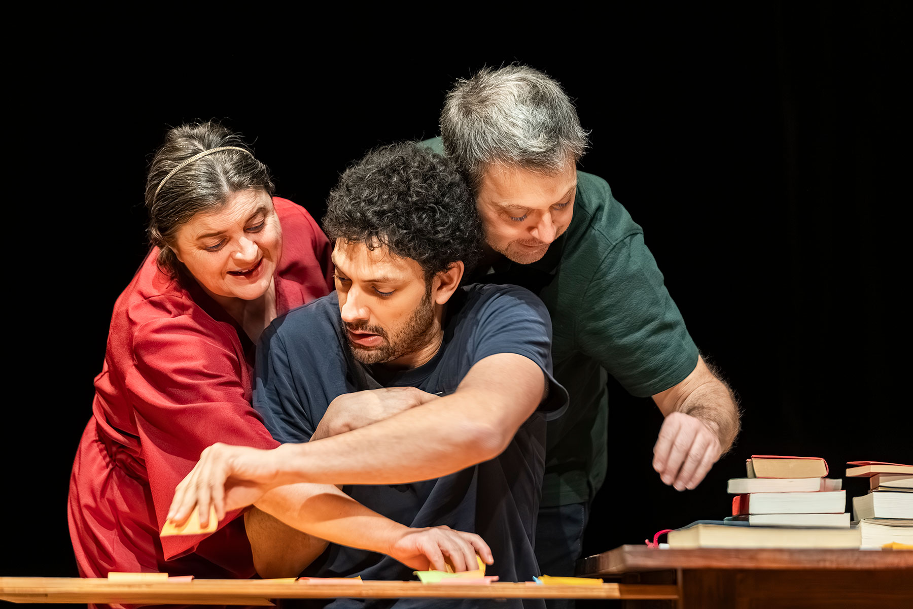 Le visuel illustre le spectacle "On n'est pas assez nombreux pour jouer Shakespeare". On voit 2 hommes et une femme, penchés sur une table jonchée de livres, qui semblent très occupés à classer, trier, évaluer.