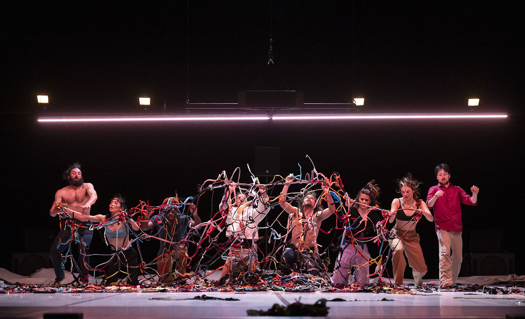 Le visuel du spectacle de danse "De loin si près" représente des danseurs contemporains vêtus de teeshirts colorés qui brandissent des bandelettes de couleur qu'ils assemblent entre elles à la manière d'un filet.