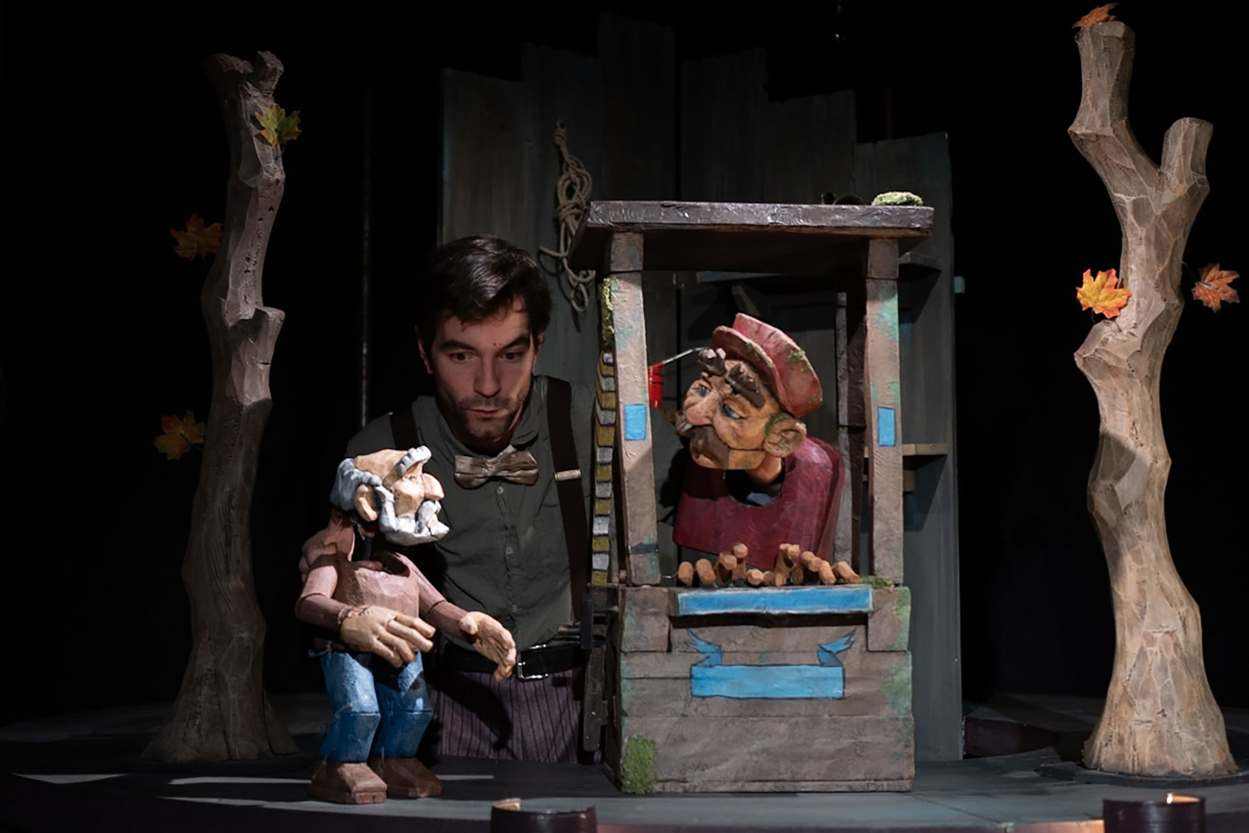 La photo du spectacle montre un petit carrousel sur lequel est posé un guichet dans lequel se trouve une marionnette masculine avec sa casquette. Ik parle avec un vieux monsieur, marionnette lui aussi, debout au pied d'un arbre en papier mâché